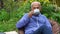 Senior man drinks tea in cozy armchair at blooming garden