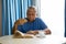 Senior man eating croissant while reading book in nursing home