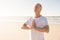 Senior man with eyes closed in prayer position at beach