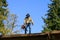 Senior man with gas powered leaf blower cleaning roof gutters on an apartment building, fall maintenance