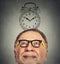 Senior man with glasses and alarm clock above his head looking up
