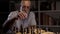 Senior man in glasses playing chess with himself at home. Leisure and entertainment concept.