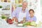 Senior man with granddaughter preparing dinner in kitchen