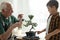 Senior man with grandson taking care of Japanese bonsai plant indoors. Creating zen atmosphere at home