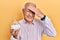 Senior man with grey hair holding bowl with sugar stressed and frustrated with hand on head, surprised and angry face