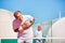 Senior man grimacing with chest pain while standing against friend during tennis match on sunny day