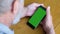 Senior man hands with smartphone green screen chroma key, close up