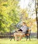 Senior man with hat sitting on a bench and reading a novel, in a