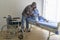 Senior man helping cancer patient woman wearing head scarf moving to wheelchairs at hospital, health care and medical concept