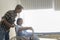 Senior man helping cancer patient woman wearing head scarf moving to wheelchairs at hospital, health care and medical concept