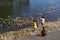 Senior man with his child feeding carp by the pond in the park in the afternoon