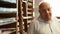 Senior man in his paper shop portrait in front of wooden shelf where are placed colored pieces of paper