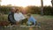 Senior man and his wife use laptop with grandson at picnic on background of sunrise