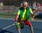 Senior man hitting a pickleball with paddle