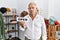 Senior man holding banner with open text at retail shop thinking attitude and sober expression looking self confident