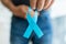 Senior man holding a blue cancer awareness ribbon