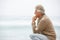 Senior Man On Holiday Kneeling On Winter Beach