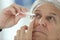 Senior man injecting serum in his eyes