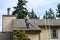 Senior man with a leaf blower on the roof of a residential home blowing debris out of gutters and off roof, fall maintenance