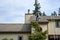 Senior man with a leaf blower on the roof of a residential home blowing debris out of gutters and off roof, fall maintenance