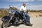 Senior man leaning on motorcycle on desert road