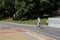 An senior man in a light sport clothes and a blue cap rides in a city park along a marked bicycle path