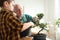 Senior man with little grandson taking care of Japanese bonsai plant indoors. Creating zen atmosphere