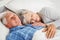 Senior man lying awake next to asleep senior woman