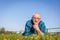 Senior man lying on the summer field in green grass.