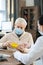 Senior man in medical mask looking at bottle of pills in front of female doctor