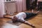 Senior man meditating on a wooden floor and lying in Shavasana pose.