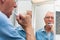 Senior man in mirror brushing his teeth