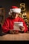 Senior man opens and reads a Christmas letter to Santa Claus while sitting in his home office