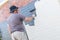 Senior man painting the exterior of a brick suburban home