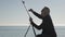 Senior man paints a picture on the beach. Elderly male artist painting the canvas on metal easel on morning calm sea