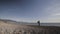 Senior man paints a picture on the beach. Long shot of elderly male artist painting on pebble sea beach background.