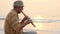 Senior man playing bamboo flute on the beach at sunset