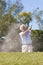 Senior Man Playing Golf Shot In a Bunker