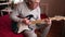 Senior man is playing guitar. Elderly man sitting on the sofa and playing guitar. Portrait of a gray-haired mature man