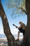 Senior man playing guitar while standing on big tree at riverside