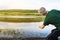 Senior man playing stone skipping at a lake