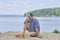 Senior man pondering a move in a game of chess and sitting on the beach near the lake