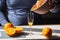 Senior man pouring squeezed orange juice from manual juicer into glass. Old man making homemade juice for breakfast.