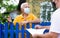 Senior man in protective mask communicating with insurance company representative while standing at fence of his country