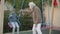 Senior man pushing swings with cute smiling boy sitting in it. Portrait of cheerful Caucasian grandfather with long grey
