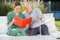 Senior Man Reading Book With Female Caretaker On