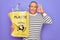 Senior man recycling holding bag with plastic bottles to recycle over purple background doing ok sign with fingers, excellent