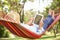 Senior Man Relaxing In Hammock With E-Book