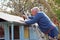 Senior man repairing shed roof.