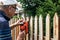 Senior man sanding wooden fence with sander